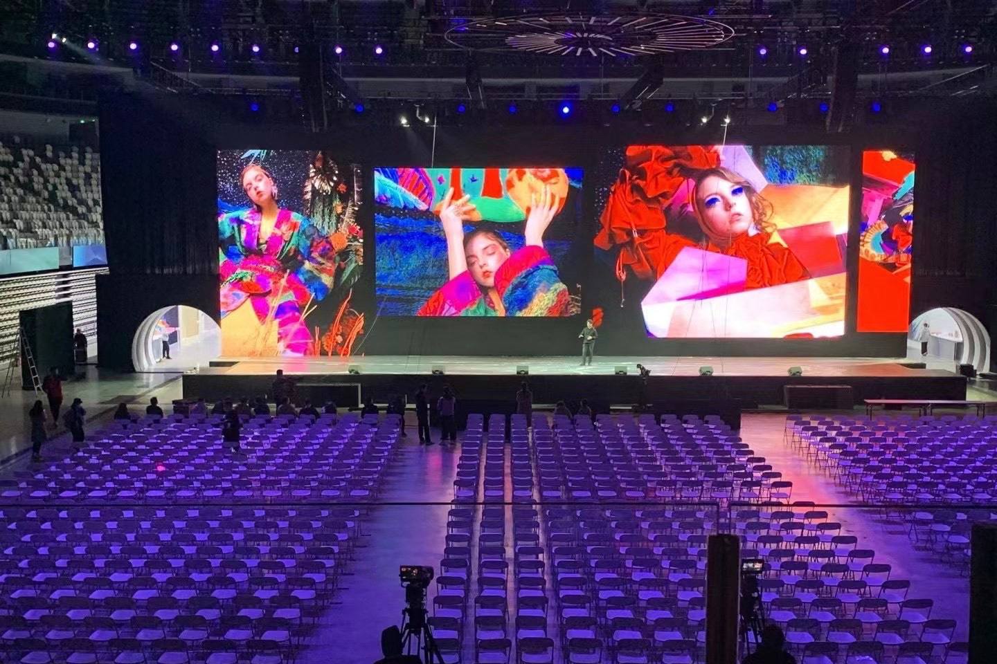 Modern event venue with LED stage displays, purple-lit seating, and professional AV setup