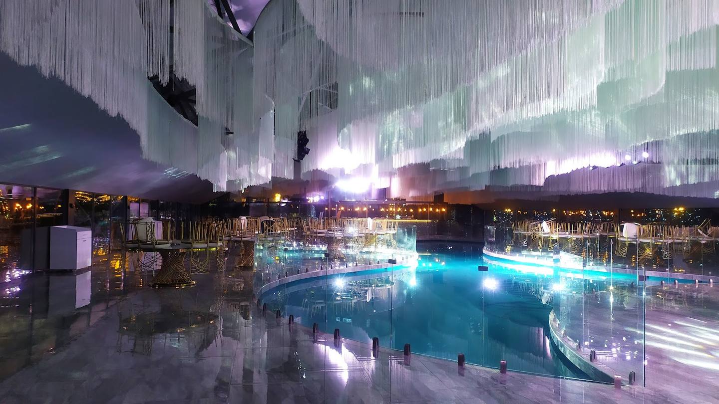 Modern indoor aquatic complex with illuminated pools and lounge areas at night