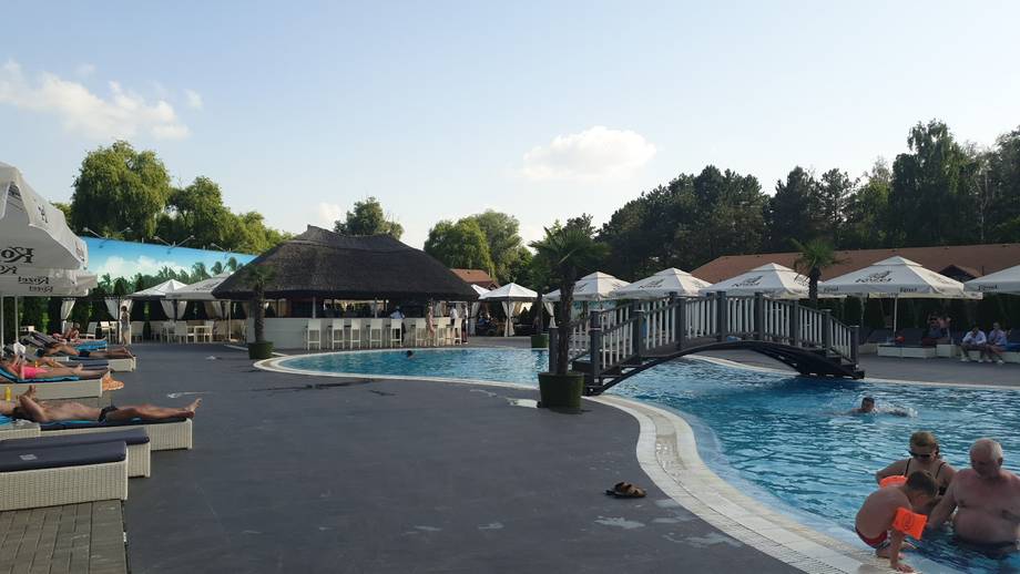 Outdoor pool complex with terrace, loungers, and recreational water areas