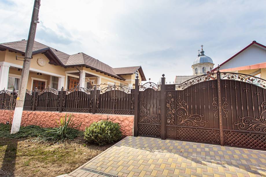 Residential property with ornate gate, brick facade, and manicured grounds