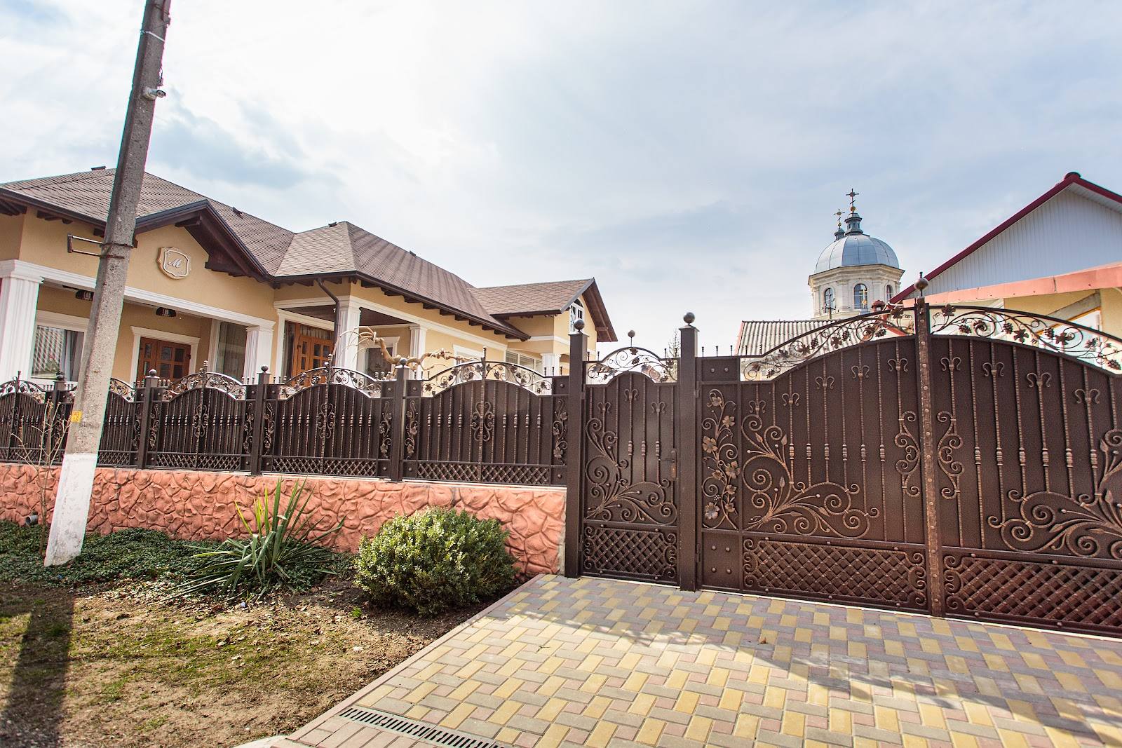 Residential property with ornate gate, brick facade, and manicured grounds