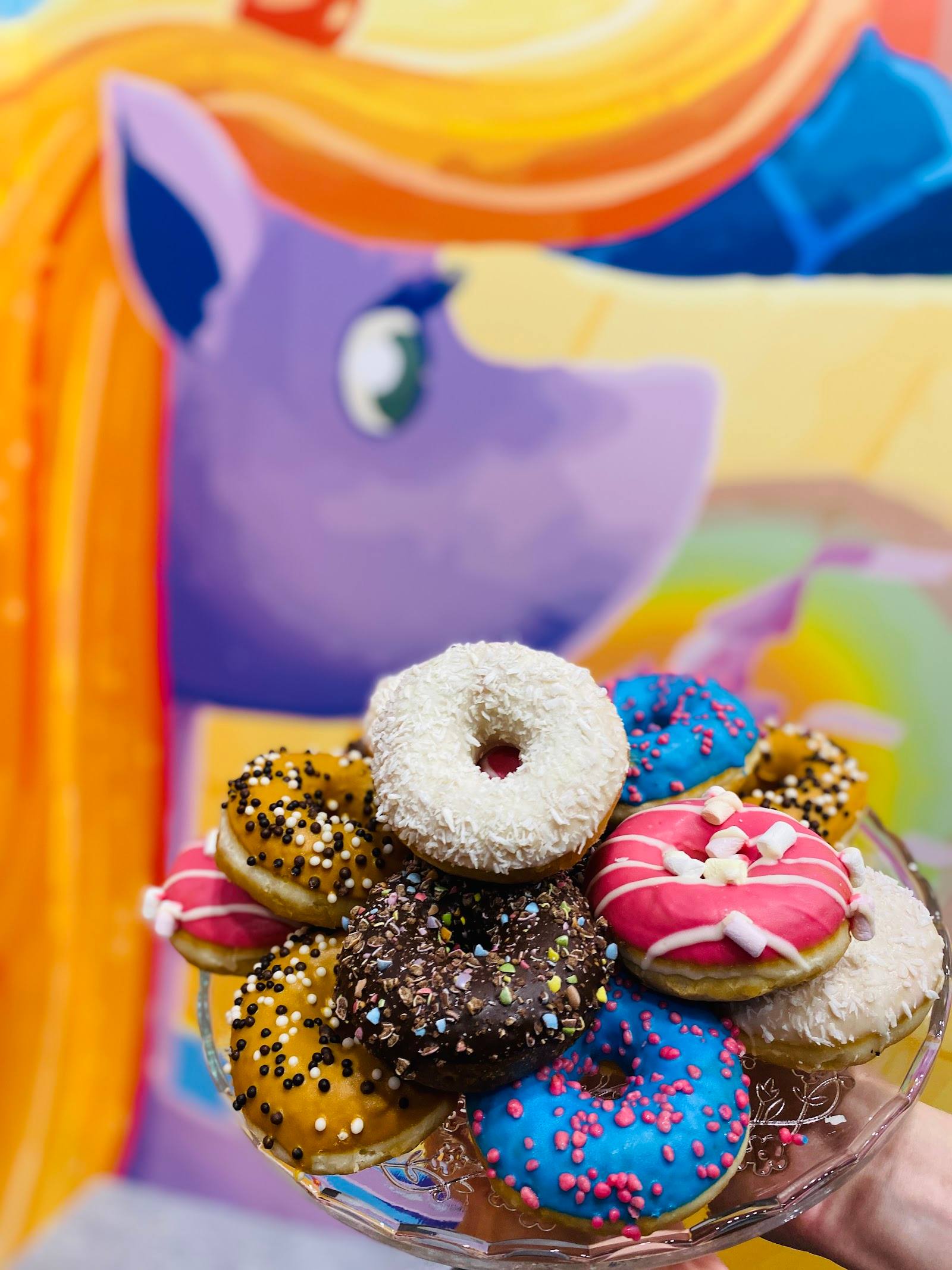 Colorful assorted donuts with sprinkles and toppings arranged on a plate