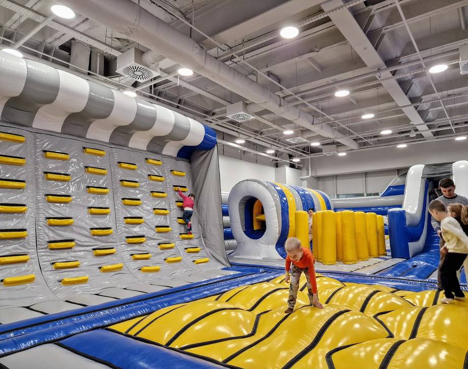Children playing in inflatable bounce house and obstacle course at indoor activity center
