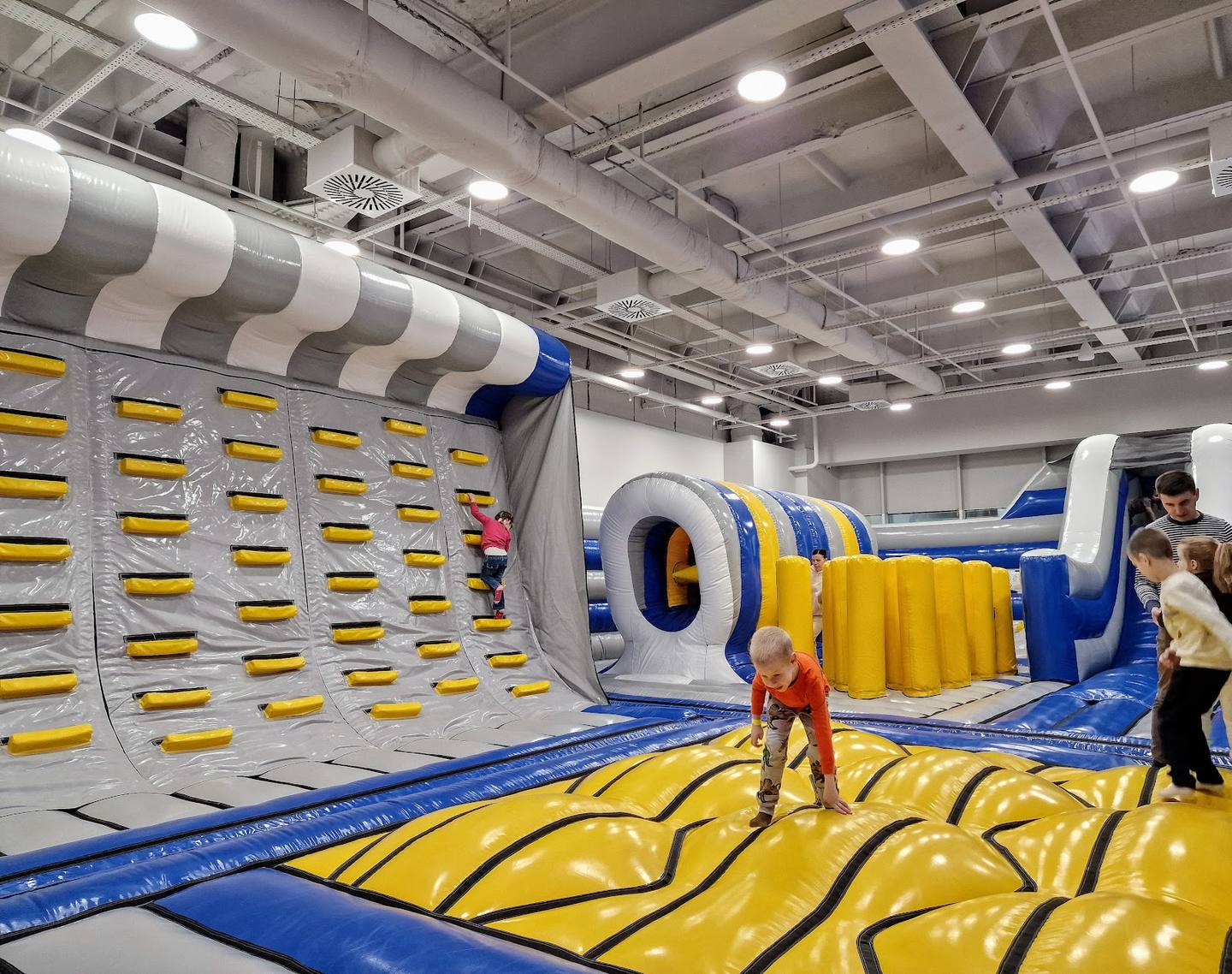 Children playing in inflatable bounce house and obstacle course at indoor activity center