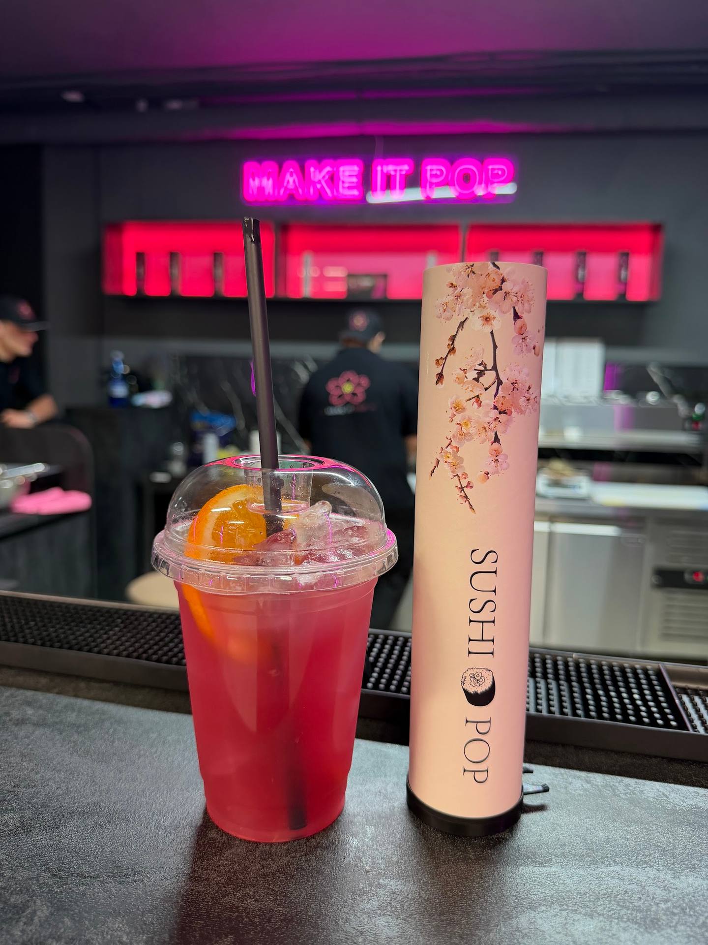 Vibrant red cocktail and lip gloss product on bar counter with neon signage