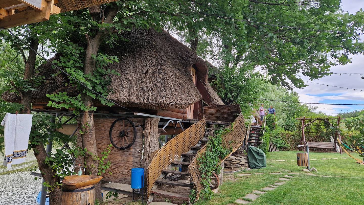 Rustic thatched-roof venue with creative wooden sculptures and lush grounds