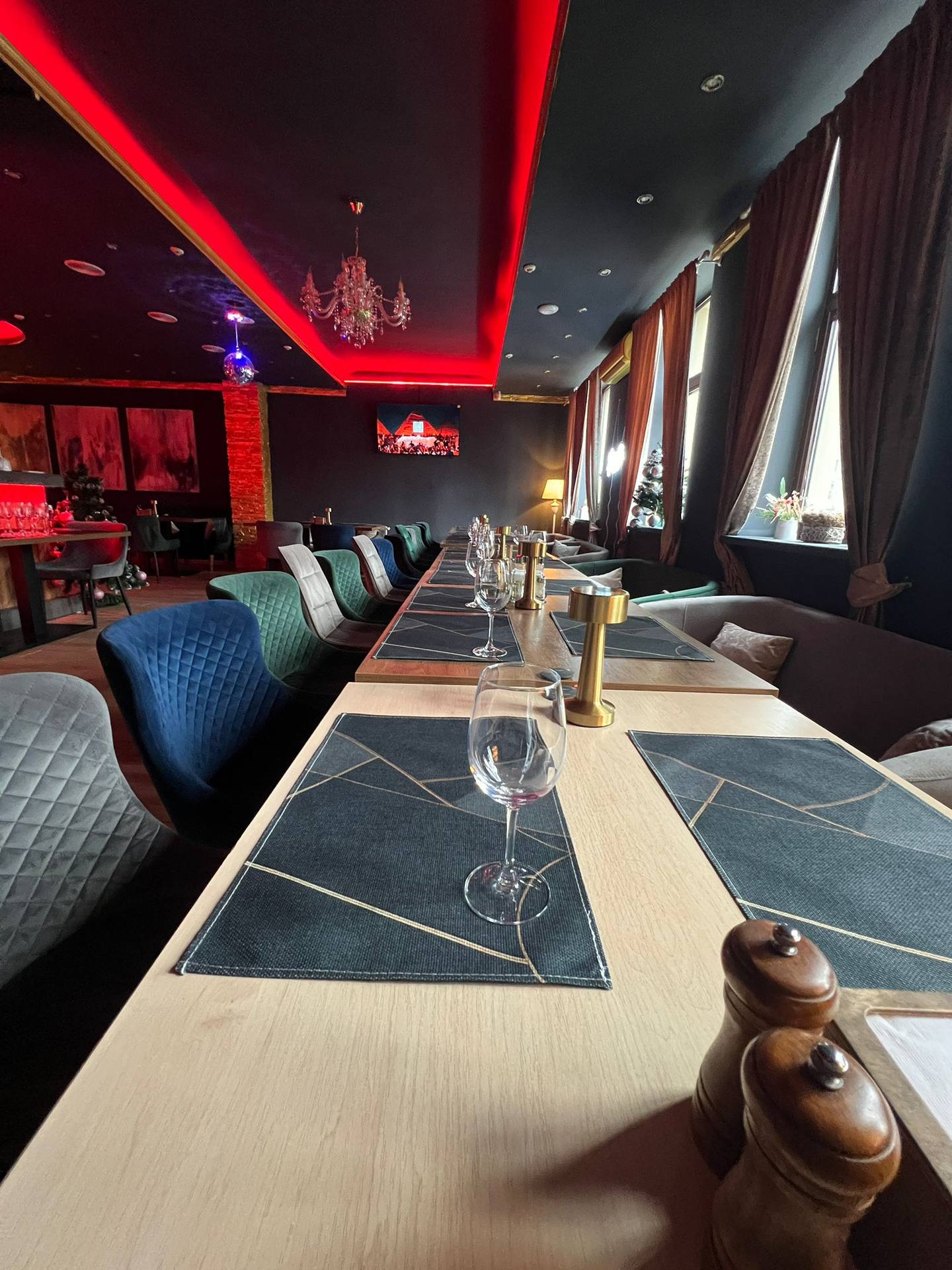 Modern upscale restaurant interior with red ambient lighting and long dining table setup