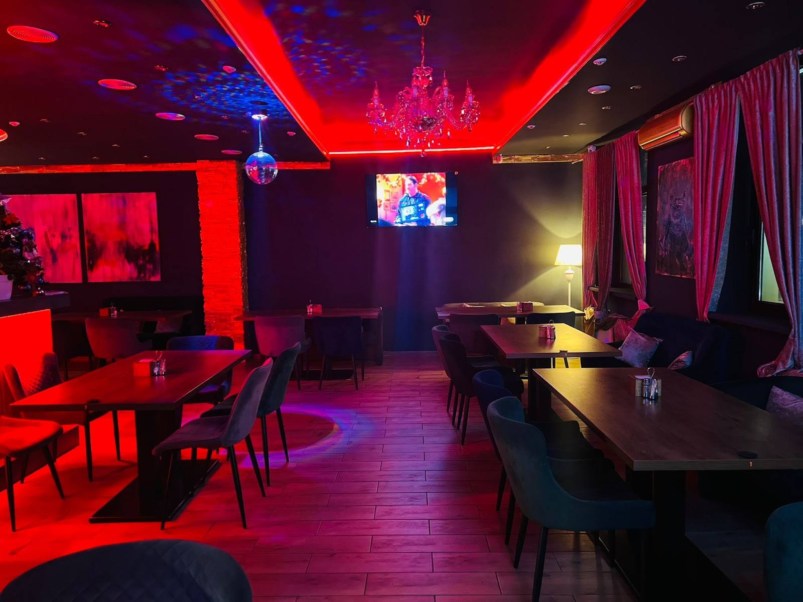 Nightclub interior with red neon lighting, bar seating, and atmospheric ambiance