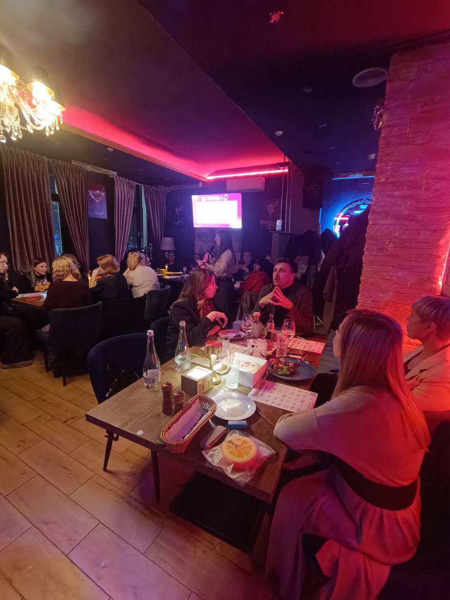 Nightclub interior with neon pink lighting, dining tables, and guests enjoying atmosphere