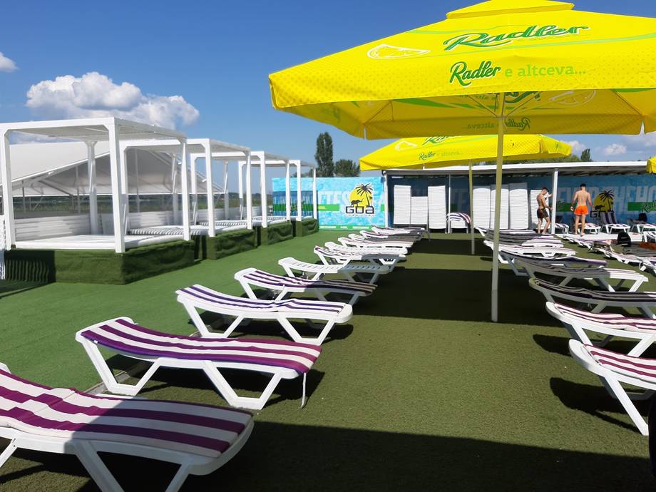 Open-air terrace with sunbeds, umbrellas, and pool access in daylight
