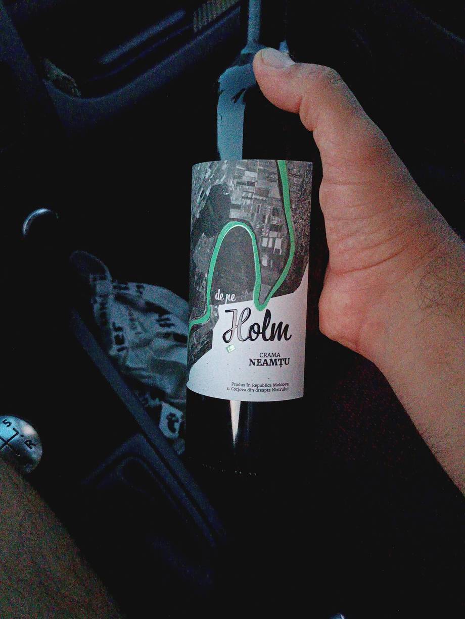 Close-up of wine bottle label held in hand against dark background