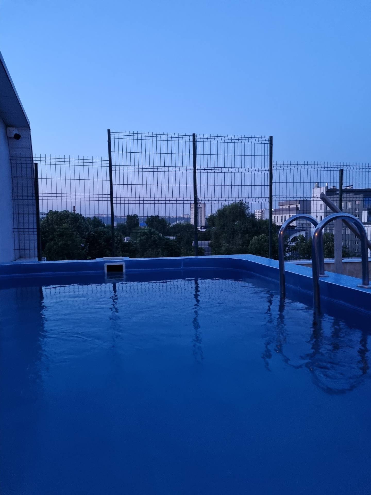 Blue water trampoline park with safety netting and surrounding landscape at dusk