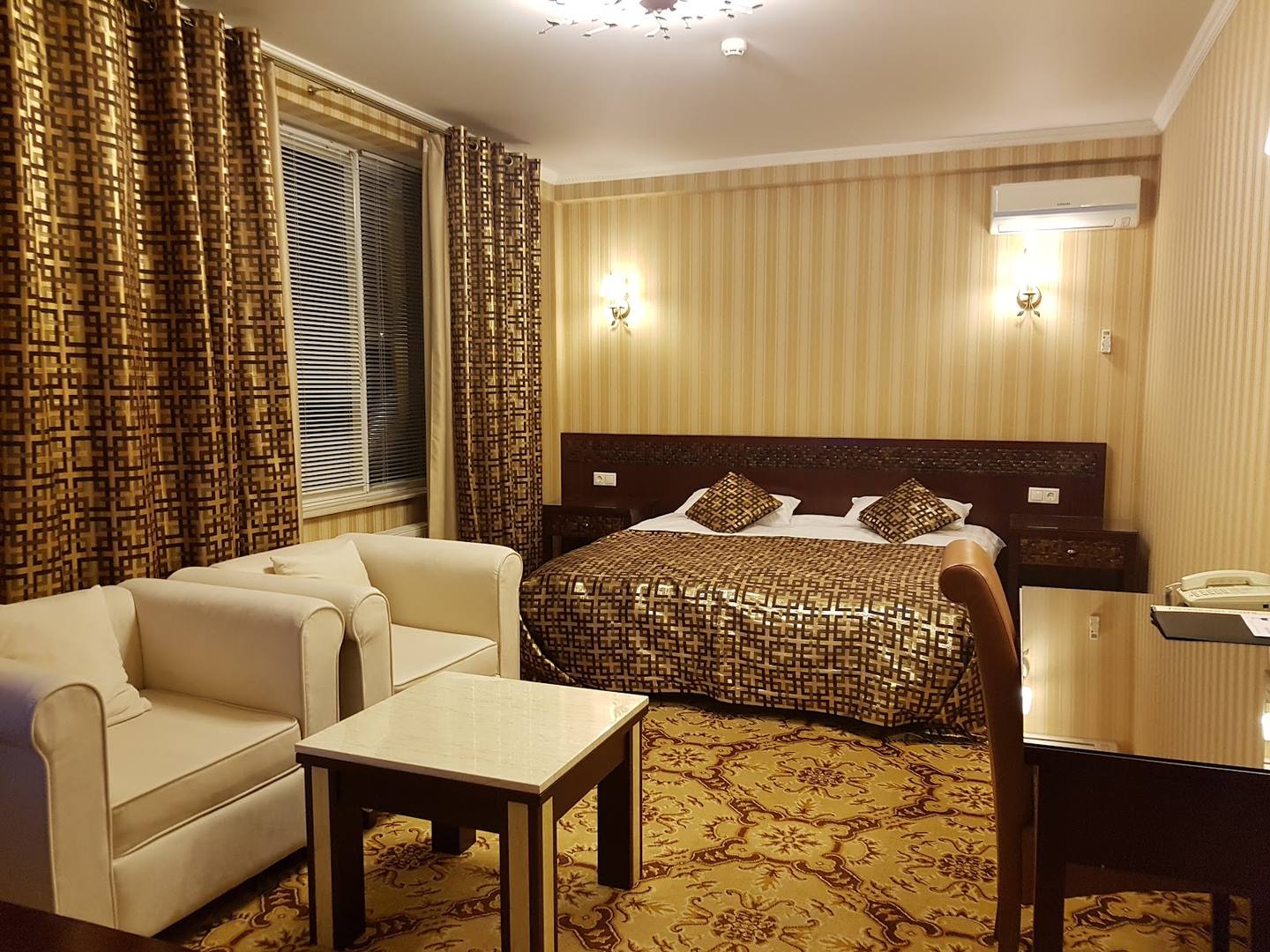 Hotel suite with warm lighting, seating area, and bed