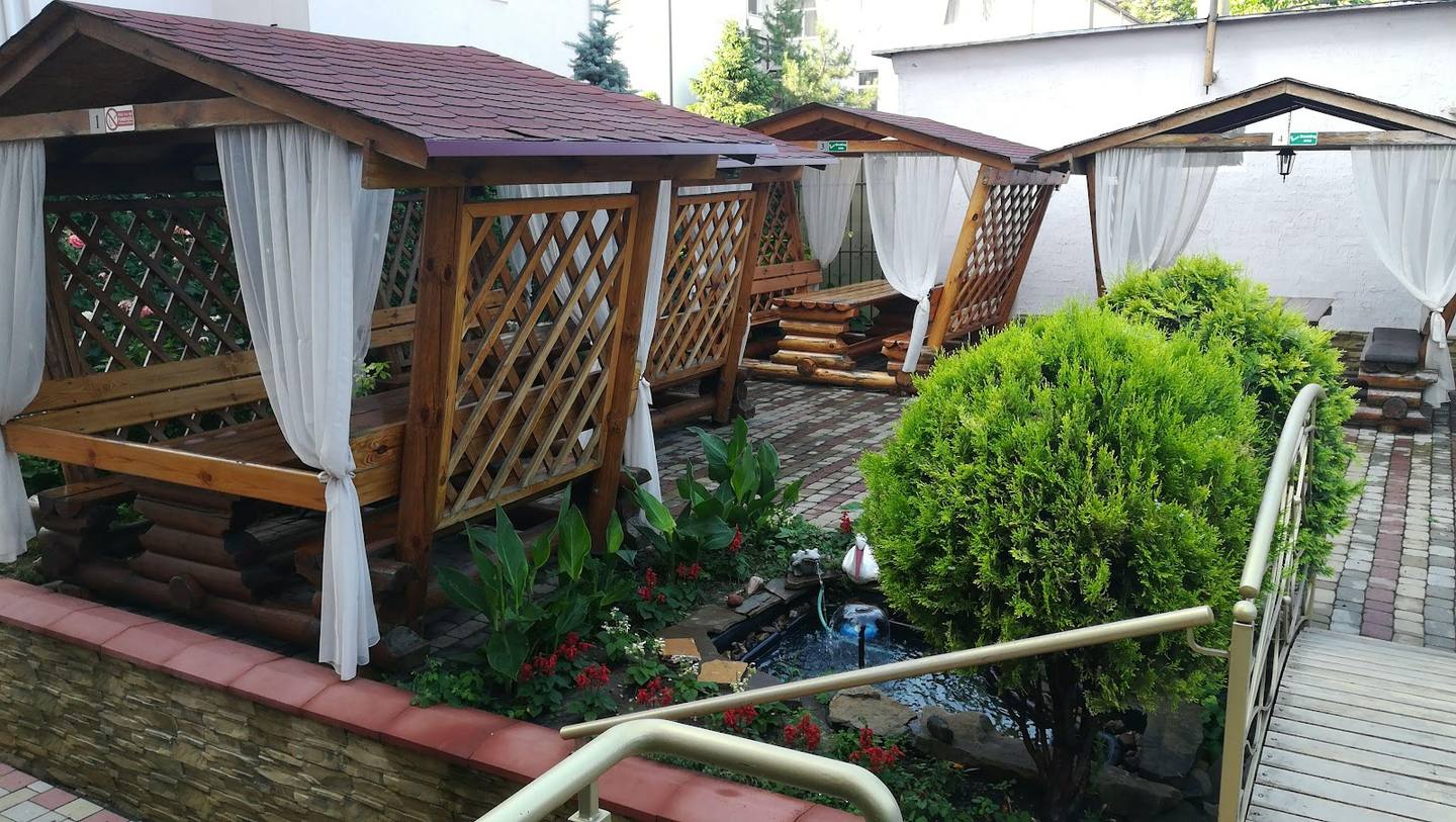 Wooden terrace with pergolas, white curtains, and garden landscaping
