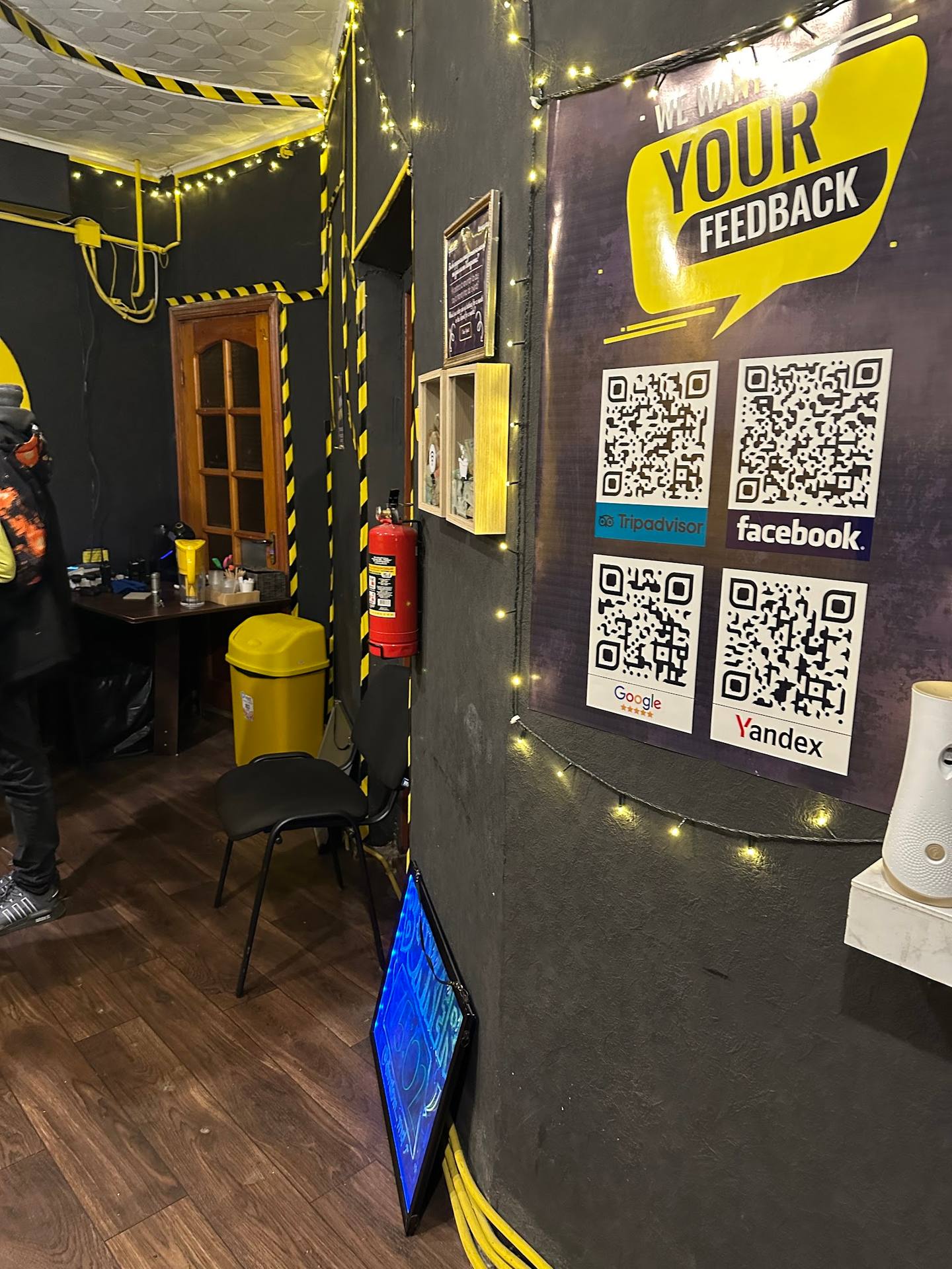 Interior of an escape room with yellow and black caution tape branding and feedback QR codes on wall