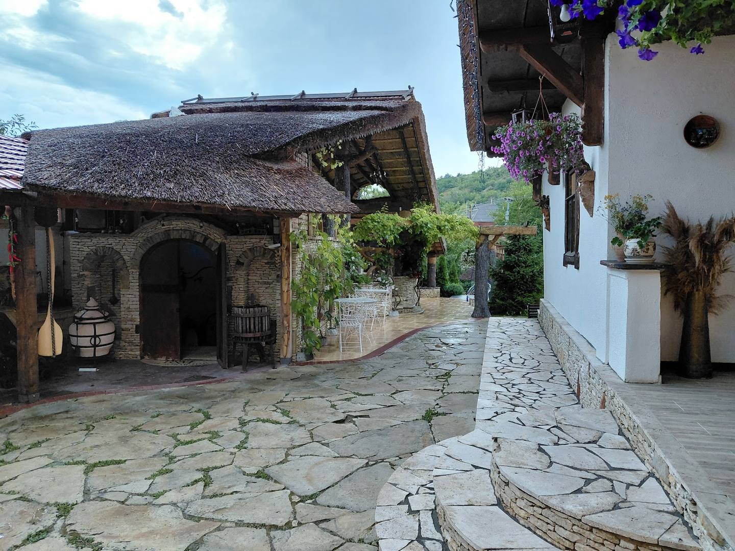 Traditional stone courtyard with thatched-roof cellar entrance and winding pathway