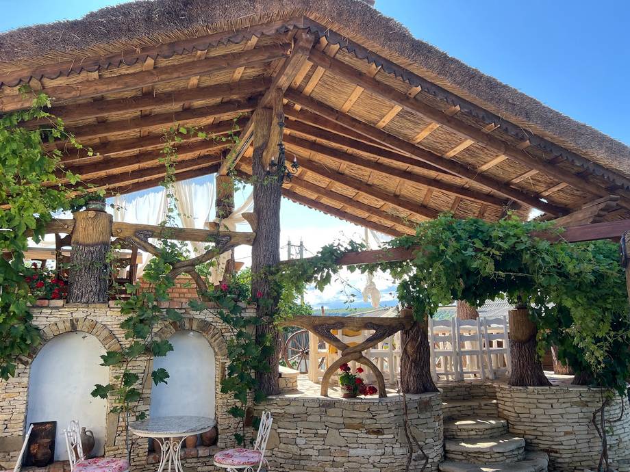 Rustic wooden pergola terrace with stone walls and climbing vines overlooking city rooftops