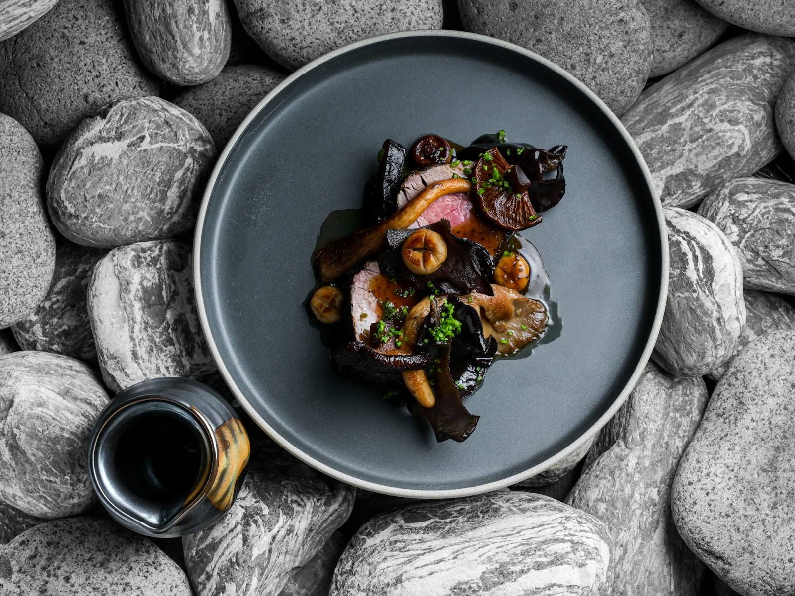 Elegantly plated seafood dish with roasted vegetables on slate plate