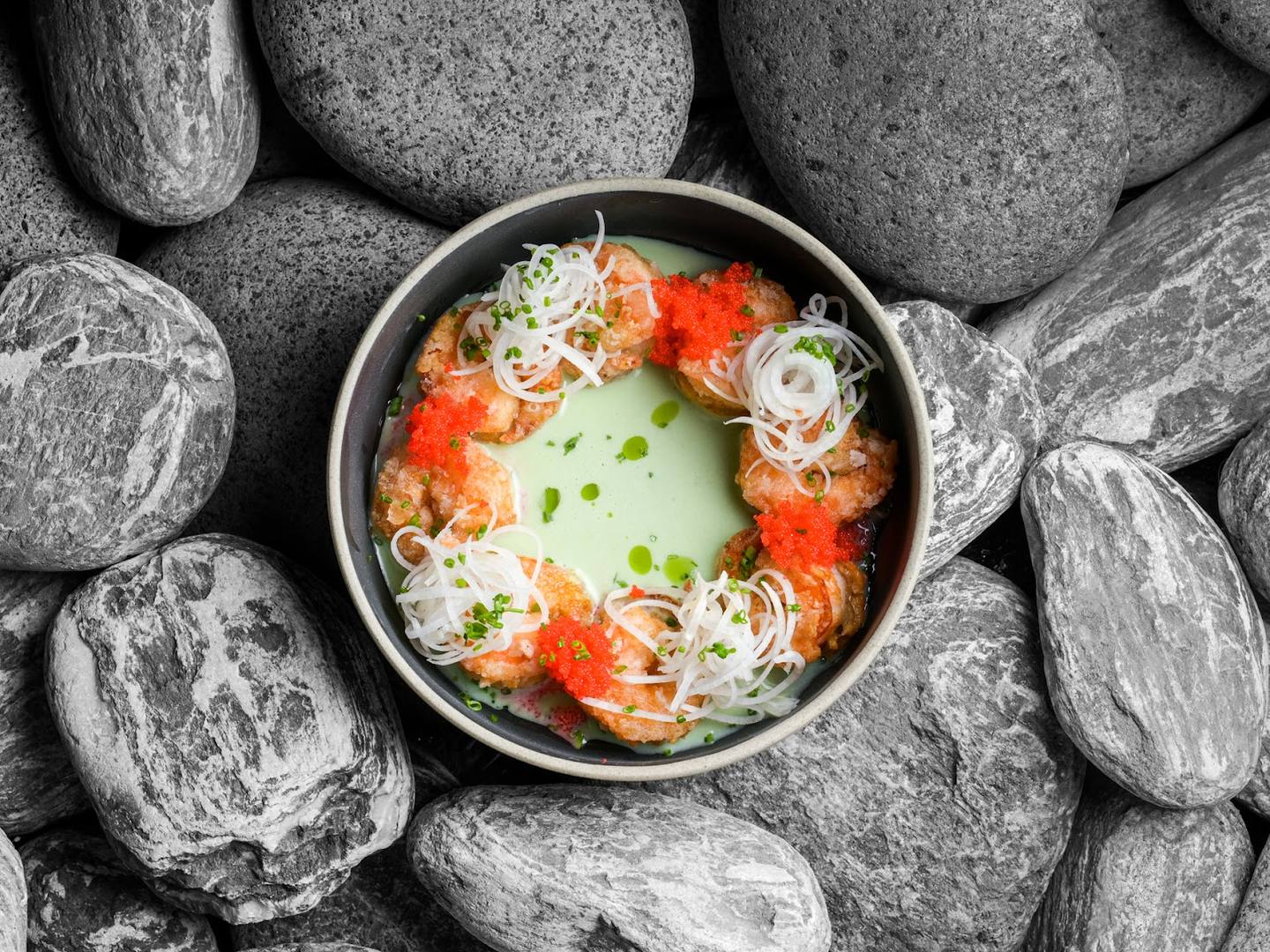 Artfully plated Asian soup or appetizer with fresh garnish and stone presentation