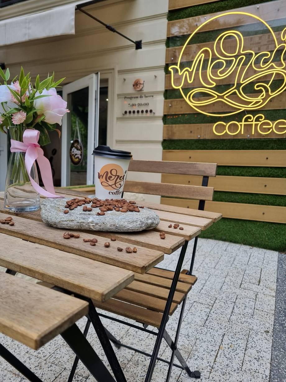 Outdoor terrace seating with neon coffee signage and branded cup at Michi Coffee