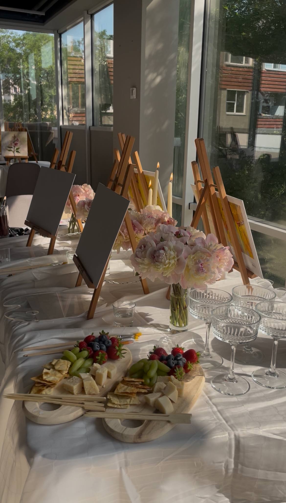 Wedding reception table setup with floral centerpieces and plated appetizers in bright terrace space