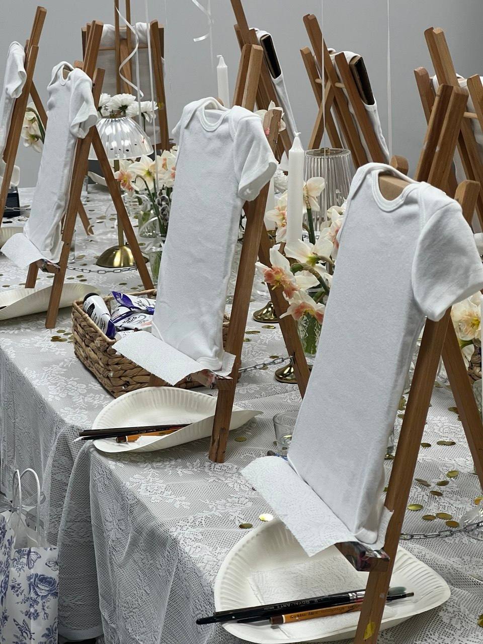 T-shirt painting or tie-dye workshop station with white garments and wooden drying racks