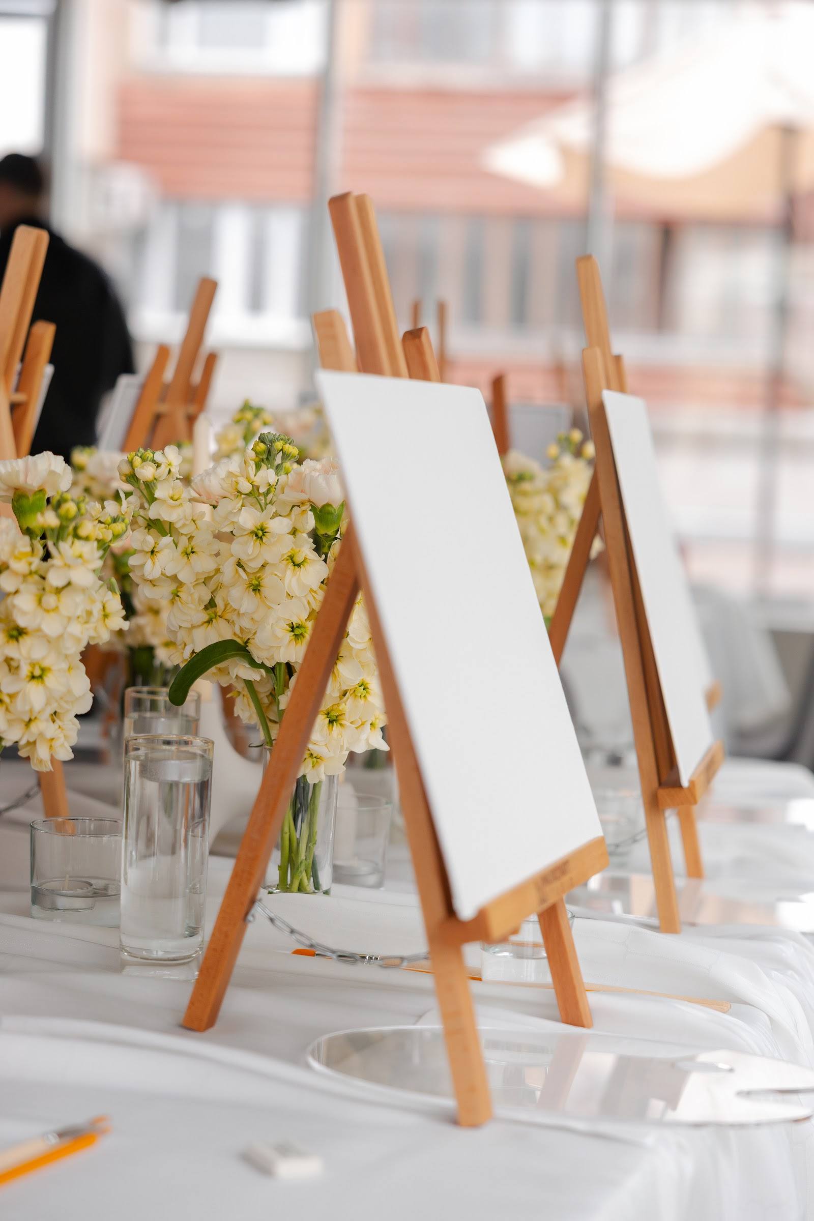 Elegant table setup with white flowers and wooden easels at an event venue