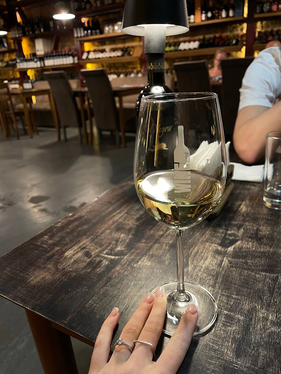 Glass of white wine served at an upscale wine bar with ambient lighting and bottle displays