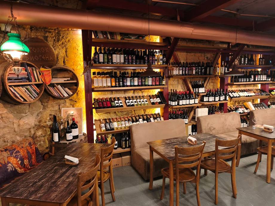 Wine bar interior with shelves of bottles, wooden tables, and warm ambient lighting