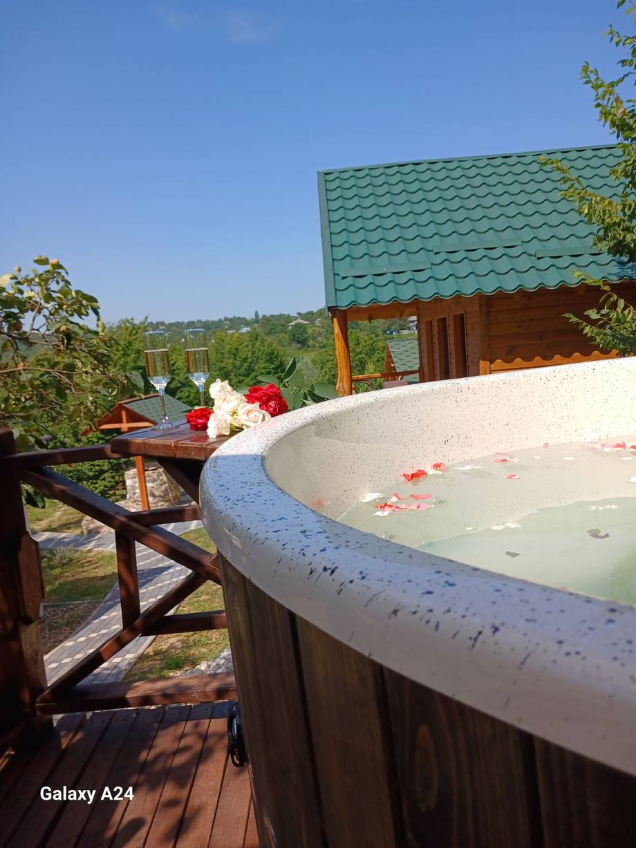 Outdoor hot tub with flower petals on elevated wooden terrace overlooking countryside