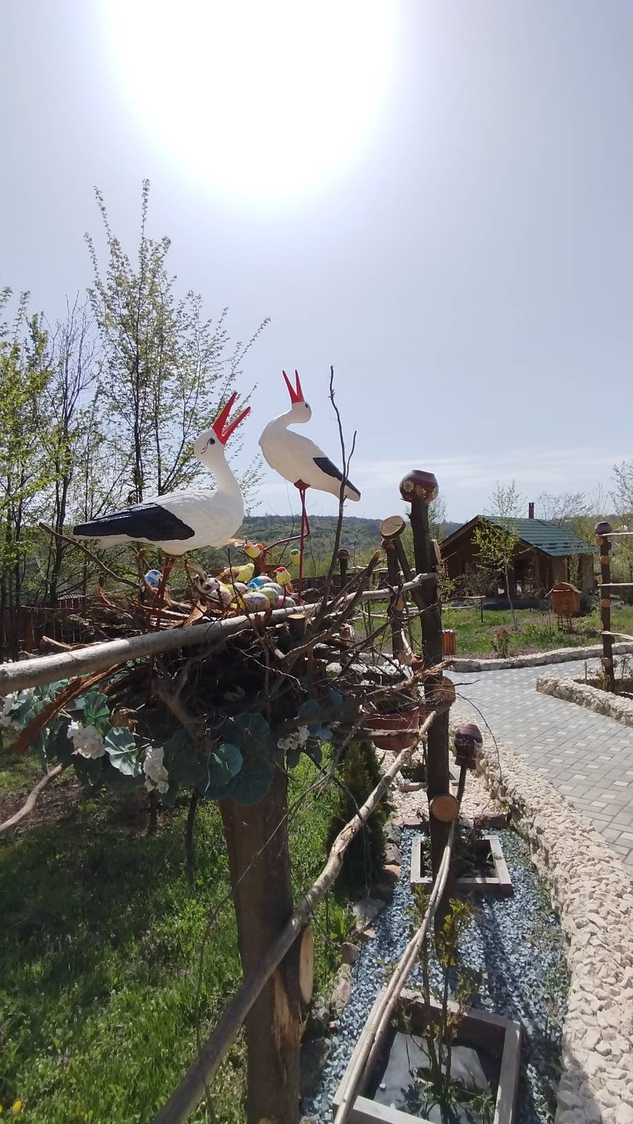 Rustic outdoor sculpture garden with traditional wooden structures and pastoral landscape
