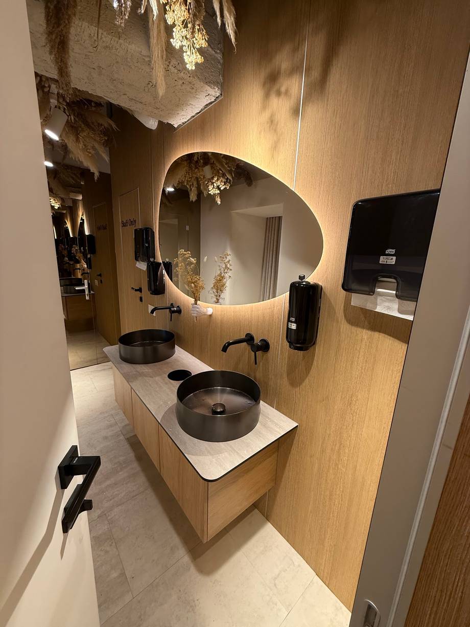 Modern spa treatment room with dual vessel sinks and illuminated mirror