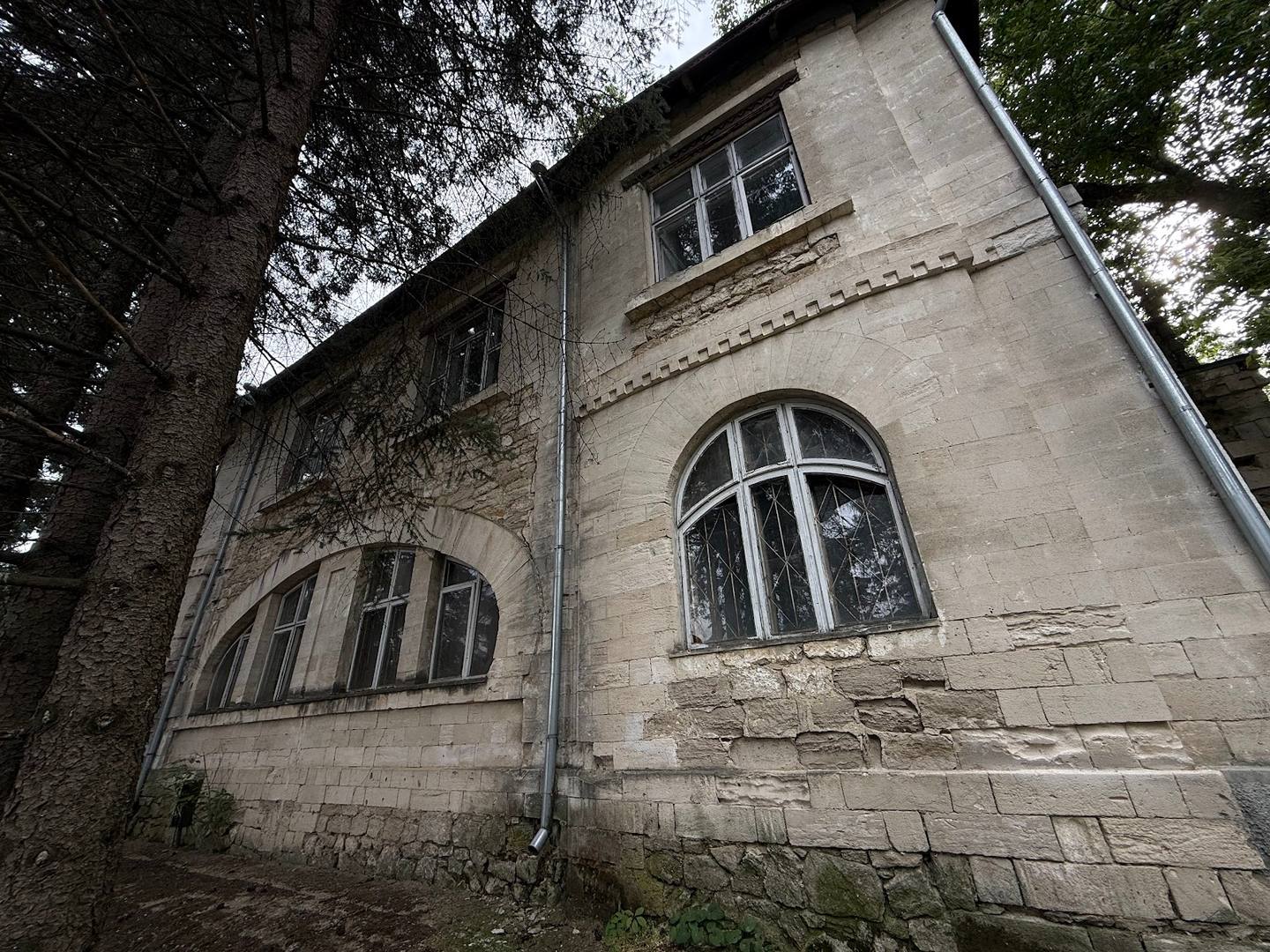 Stone monastery building facade with arched windows and ivy, Moldova