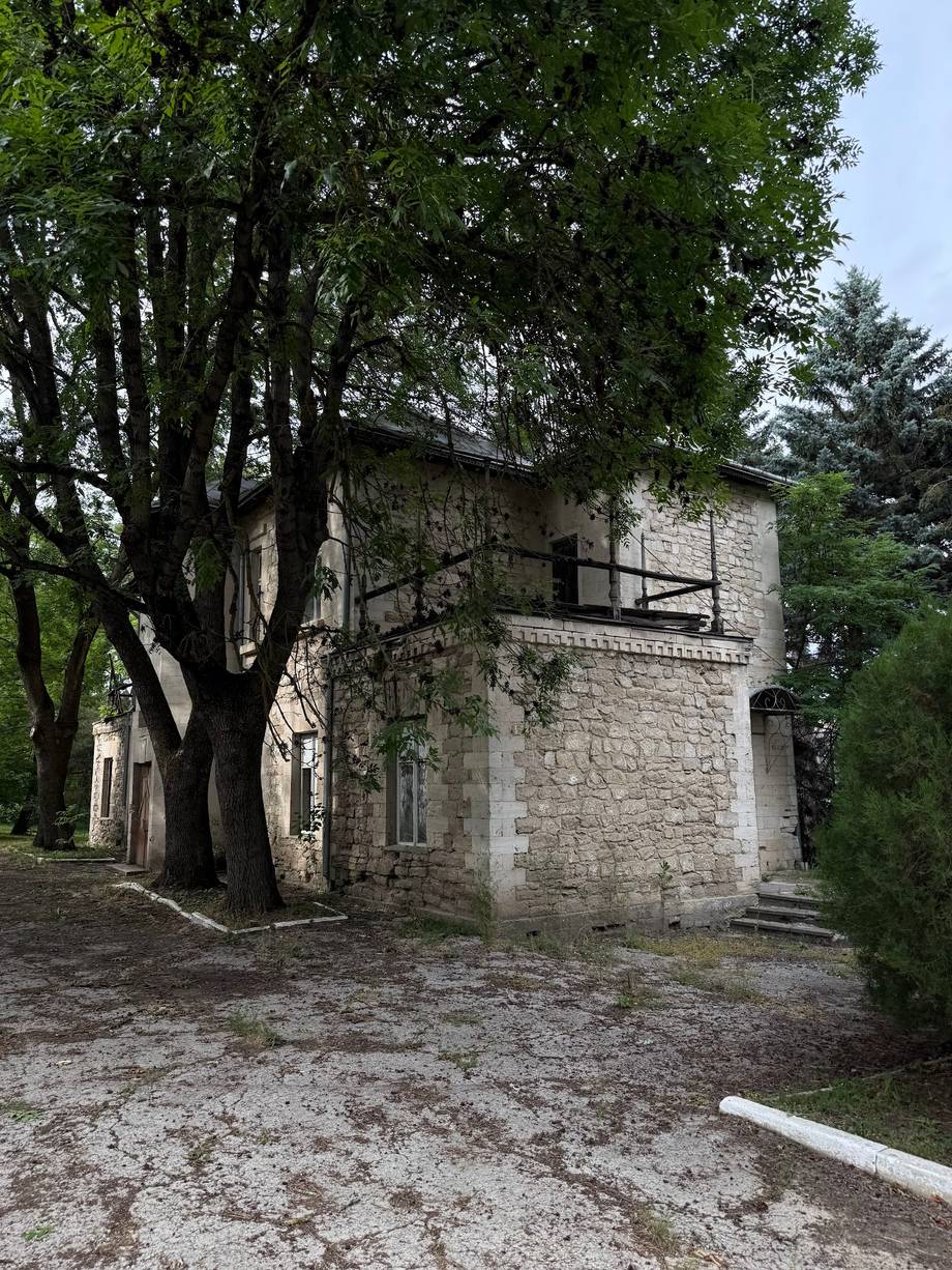 Historic stone monastery building with ancient tree and ivy-covered walls