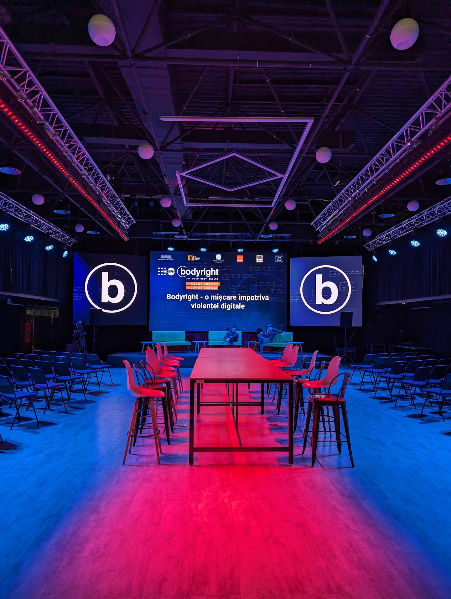Modern event space with professional lighting, branded "b" signage, and conference setup