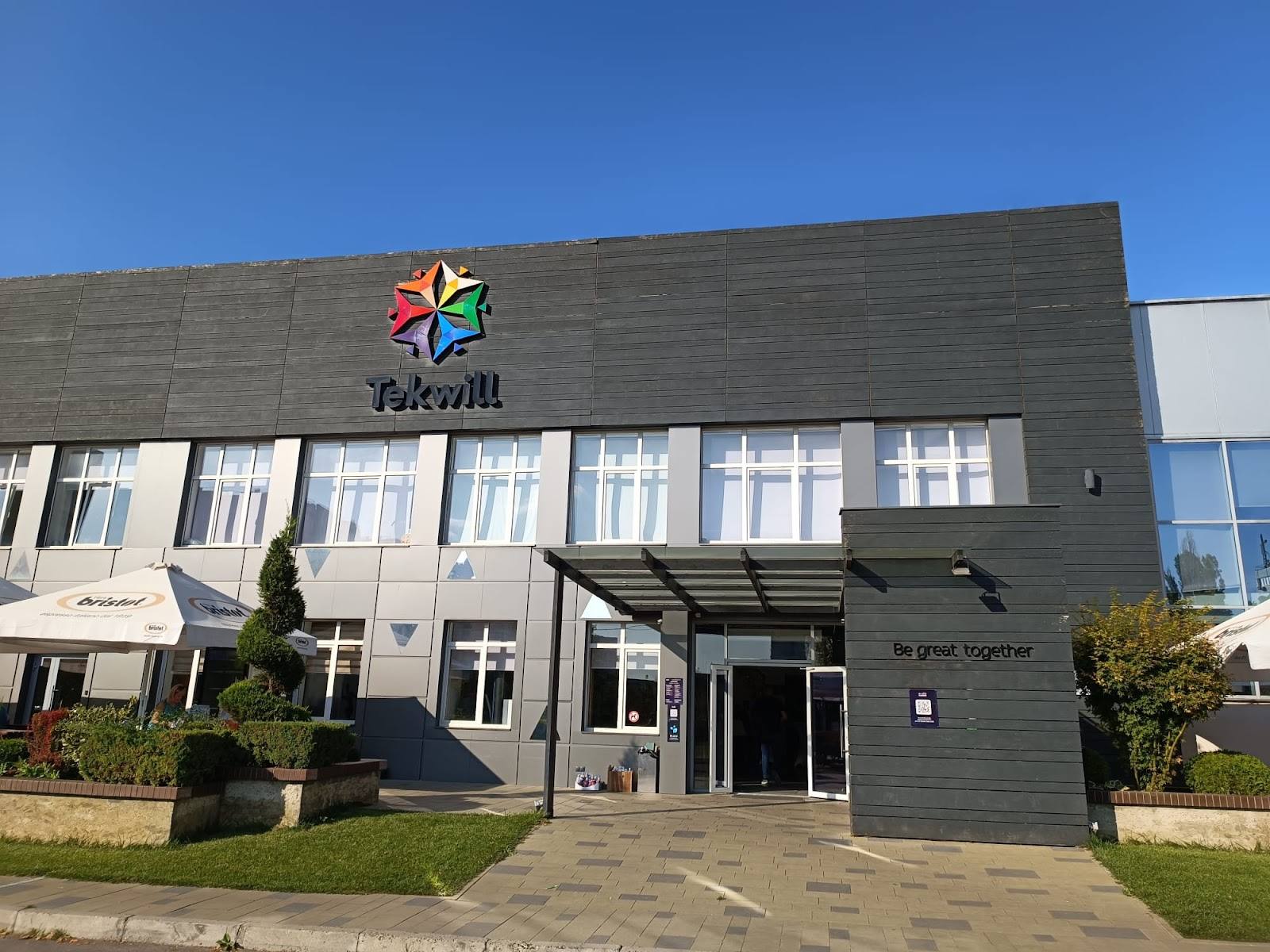 Modern storefront with colorful logo, large windows, and landscaped entrance