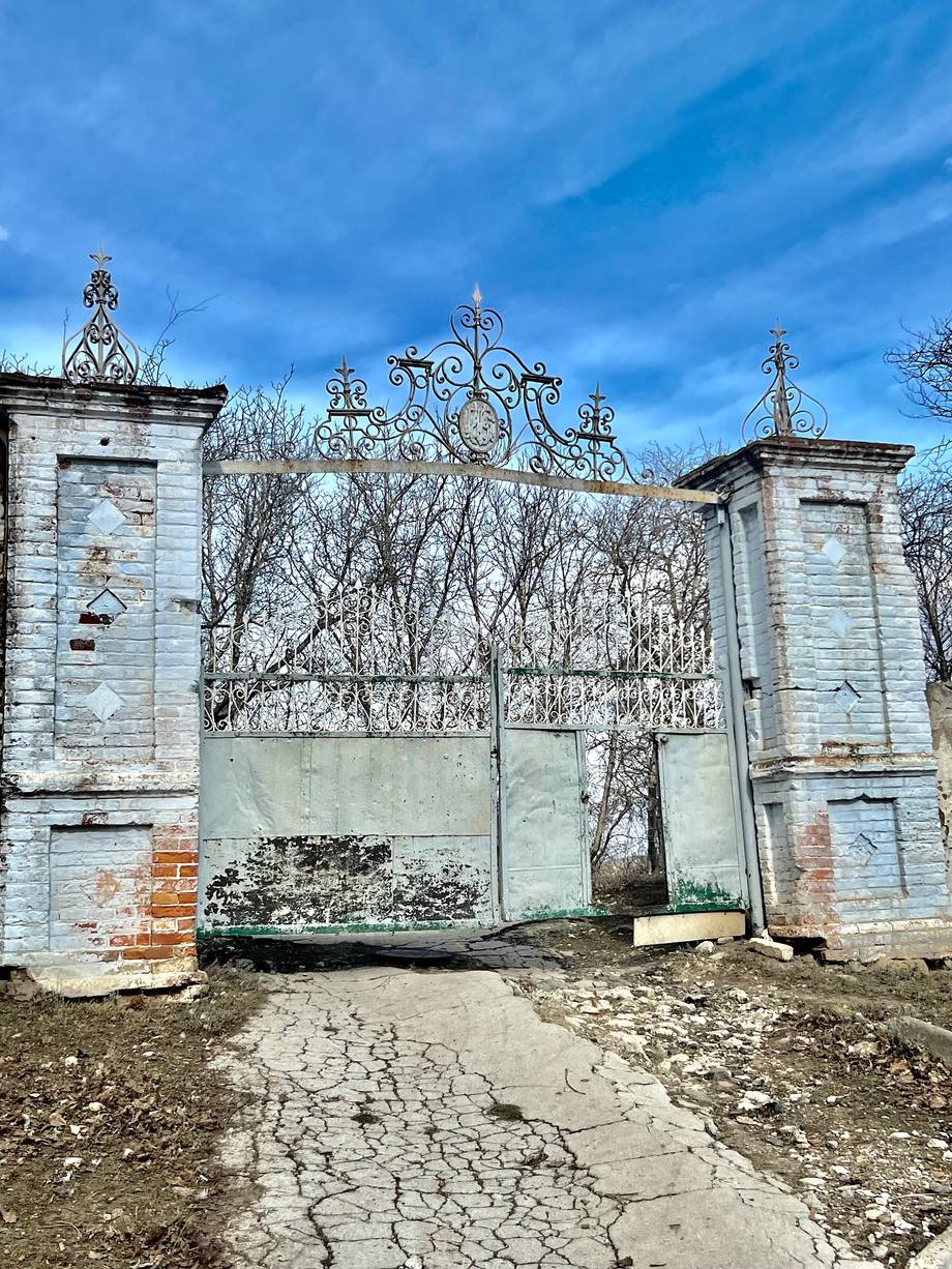 Ornate Orthodox monastery gates with twin pillars and decorative crosses under blue sky