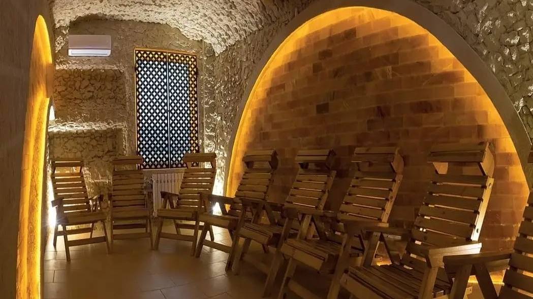Historic stone cellar with arched vault, warm ambient lighting, and wooden chairs arranged for events