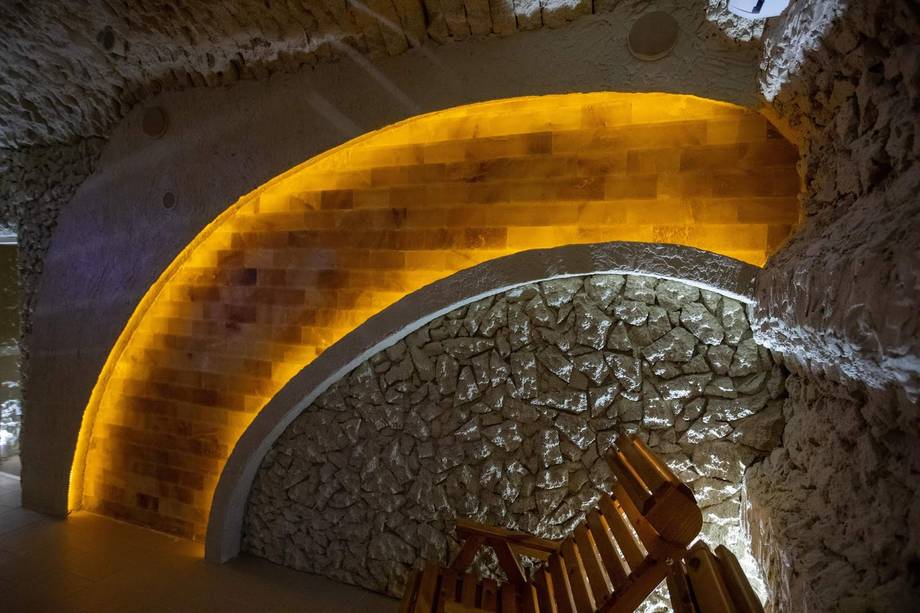 Arched stone cellar with amber accent lighting and wooden staircase