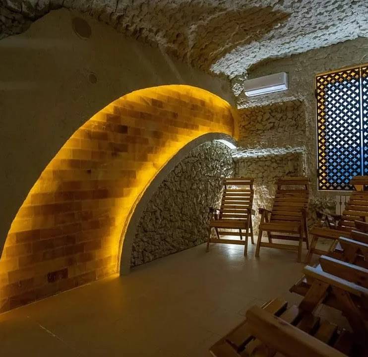 Wine cellar with stone arches, warm accent lighting, and wooden seating
