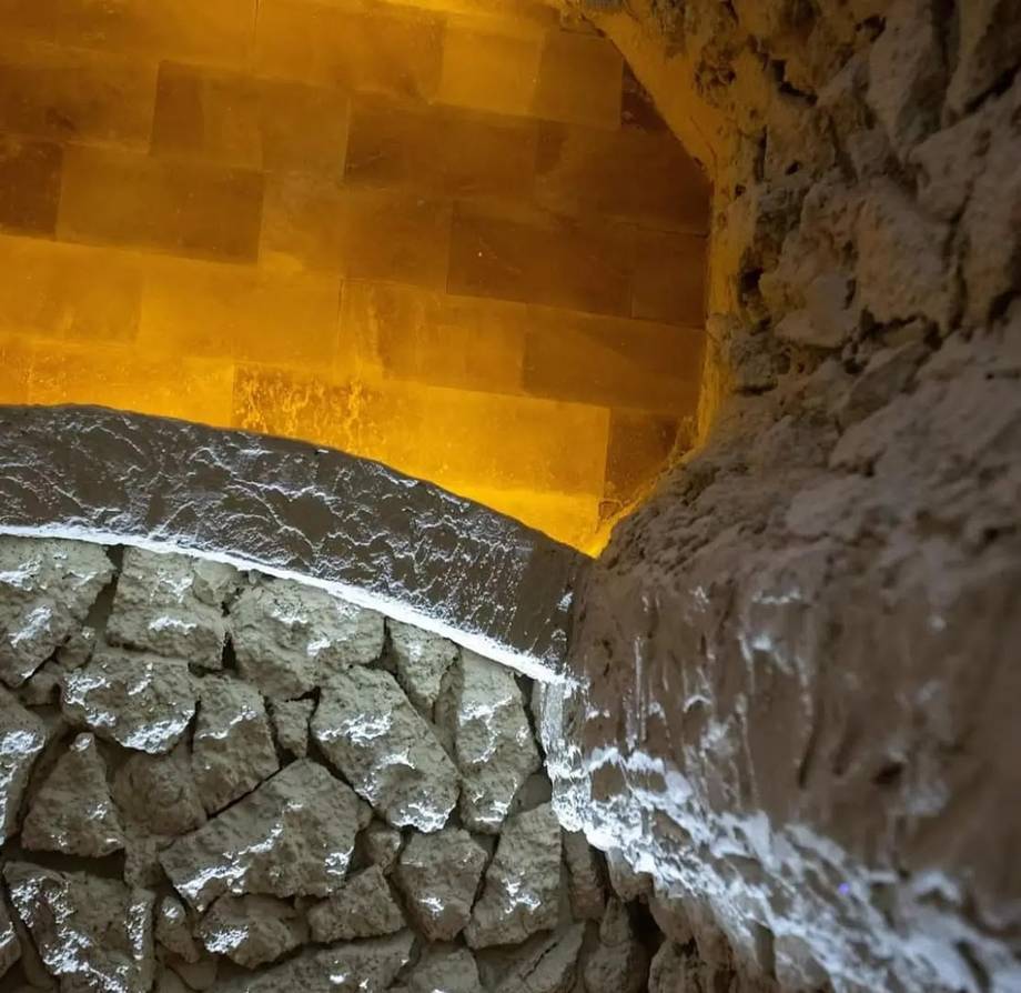 Close-up of wine cellar barrel detail with aged stonework and yellow lamp