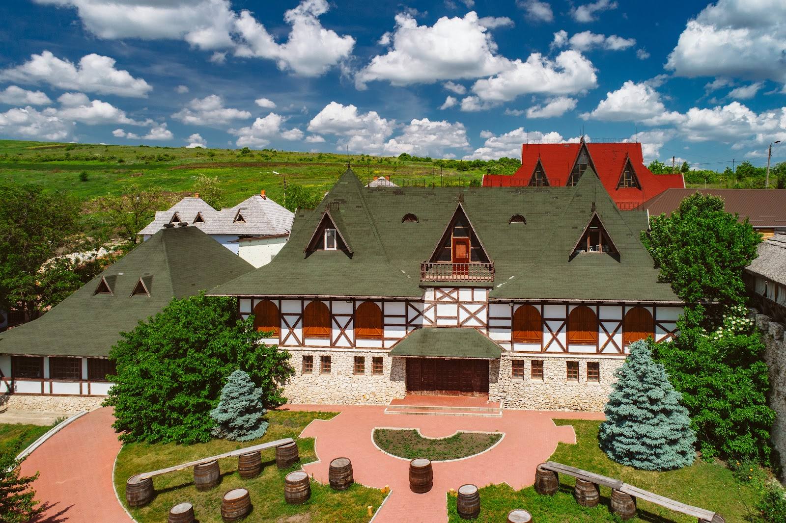 Historic monastery complex with half-timbered main building and red-roofed chapel, aerial view