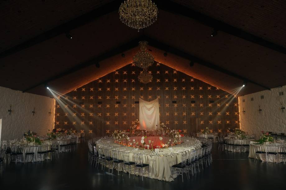 Elegant wedding reception venue with dramatic backdrop lighting and crystal chandelier
