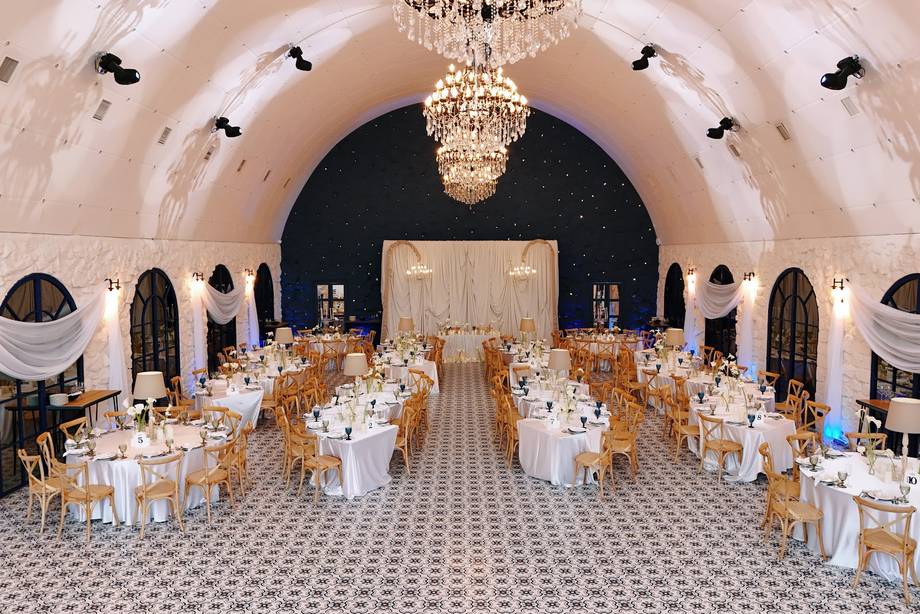 Elegant arched wedding reception hall with crystal chandelier and draped seating