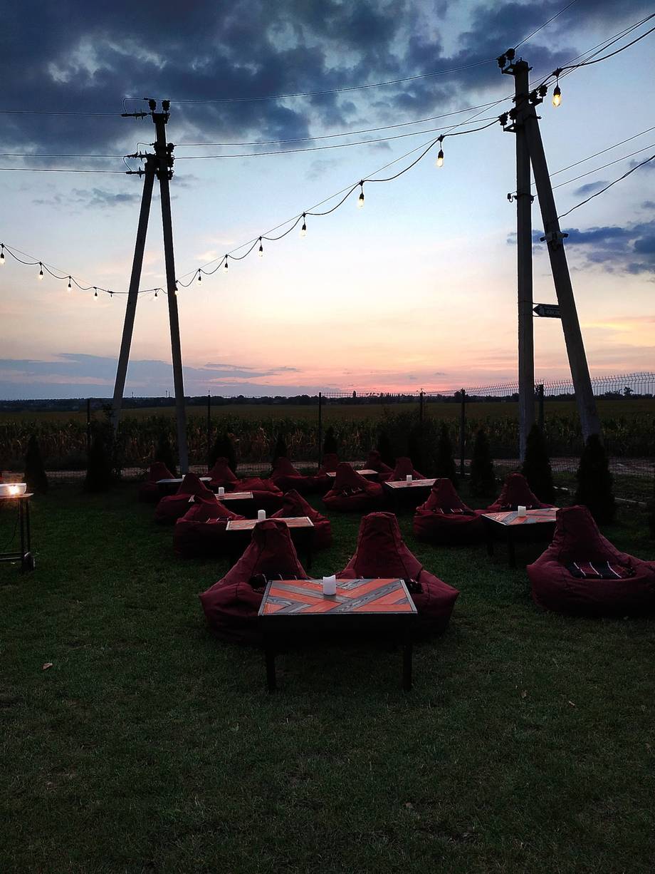 Open-air terrace with burgundy lounge seating under string lights at dusk