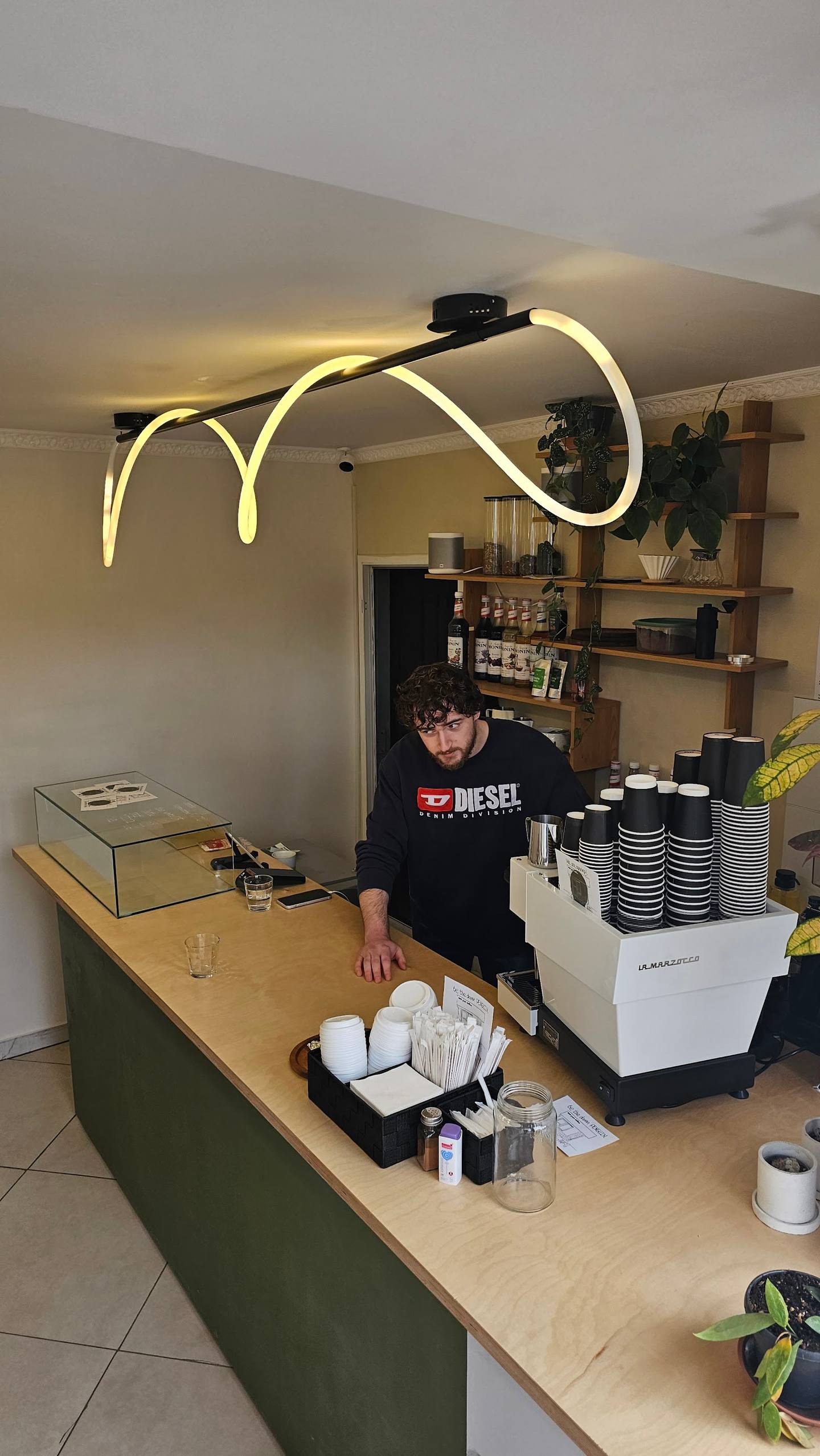 Café counter with neon signage and barista at service station
