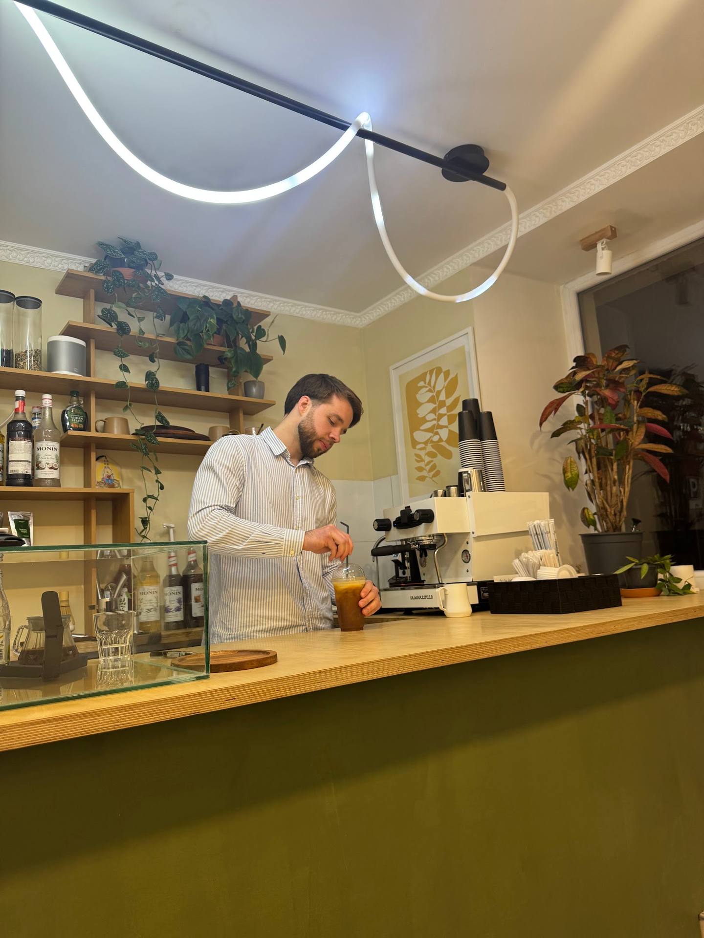 Bartender preparing a cocktail at wooden counter with shelving and ambient neon lighting