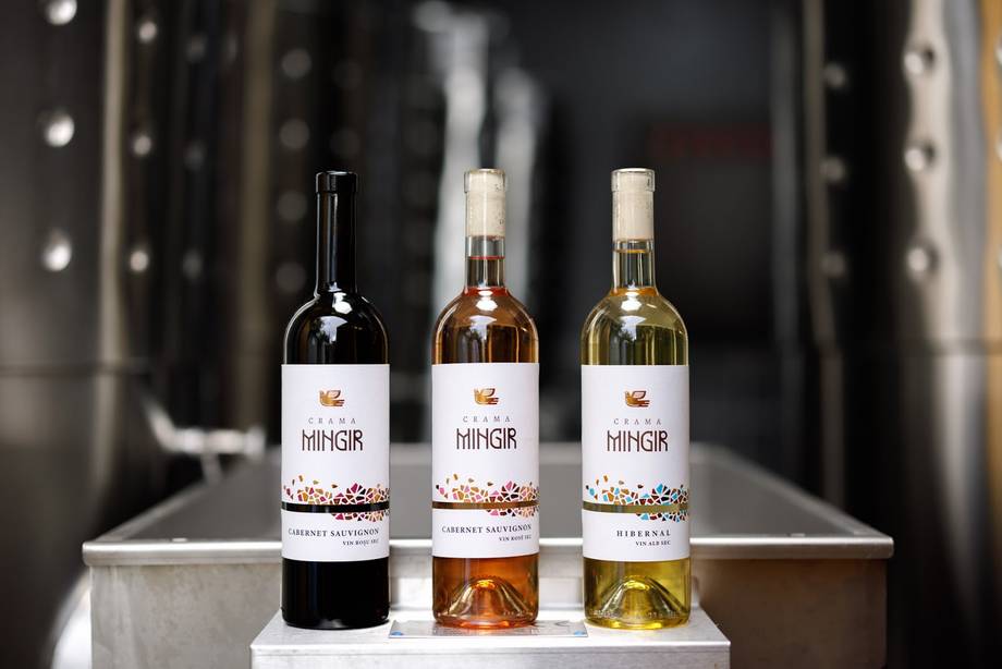 Three MINER wine bottles in red, rosé, and white varieties displayed on white podium