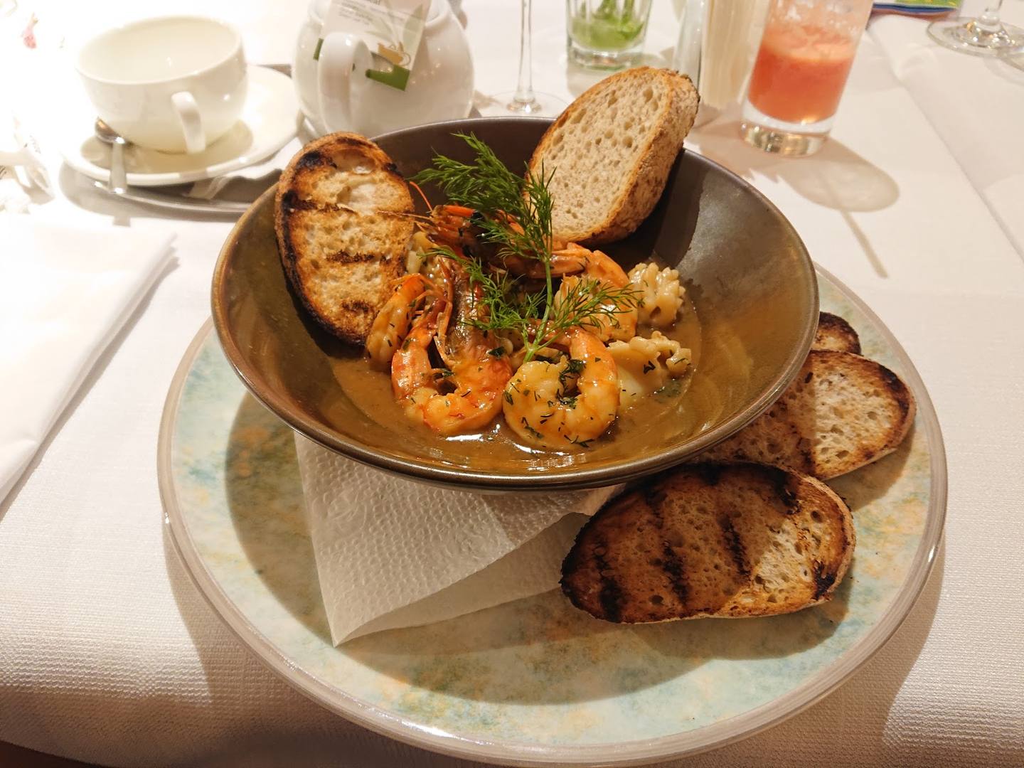 Grilled seafood and bread plated at table with white linens