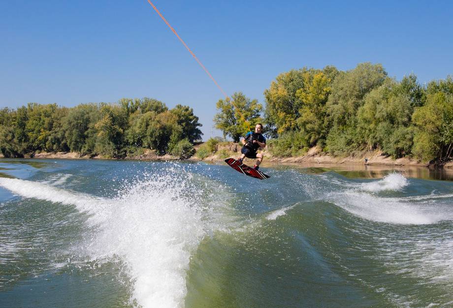 Wakeboarder performing tricks on river with natural vegetation backdrop